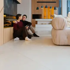 Para przytulająca się na jasnej, lśniącej posadzce w nowoczesnym salonie.