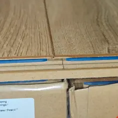 Zbliżenie na podłogę laminowaną z niebieską warstwą izolacyjną. Pokazuje, czy można położyć panele na panele, ukazując strukturę podłogi.