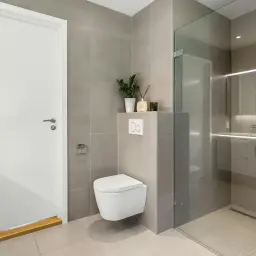 Nowoczesna łazienka z prysznicem walk-in i podwieszaną miską WC. Eleganckie płytki i minimalistyczne dodatki sprawiają, że remont łazienki niskim kosztem wygląda luksusowo.