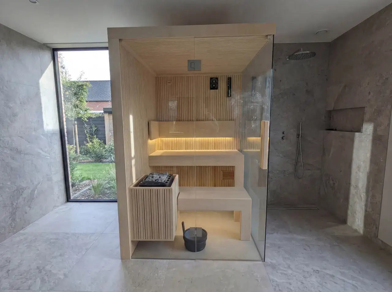 Nowoczesna sauna w łazience, z przeszklonymi drzwiami i widokiem na ogród.