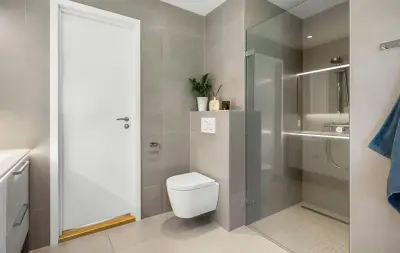Nowoczesna łazienka z prysznicem walk-in i podwieszaną miską WC. Eleganckie płytki i minimalistyczne dodatki sprawiają, że remont łazienki niskim kosztem wygląda luksusowo.
